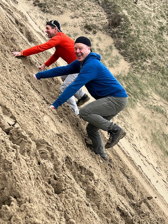 Scott and friend scaling a sandy vertical hill pain free and happy