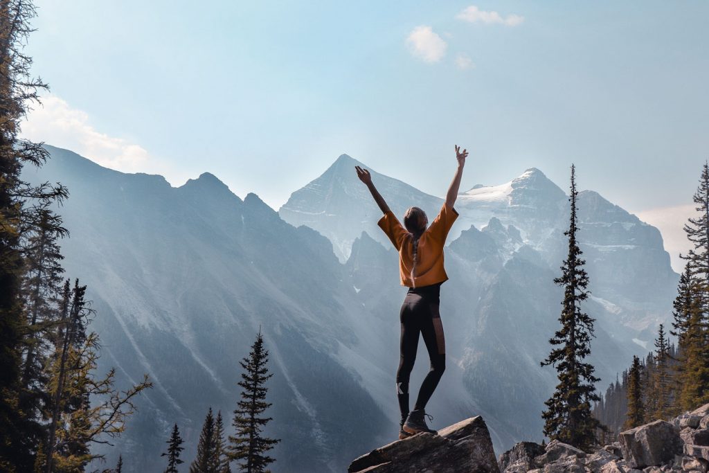 Girl looking away with arms raised in triumph. she has been hiking
